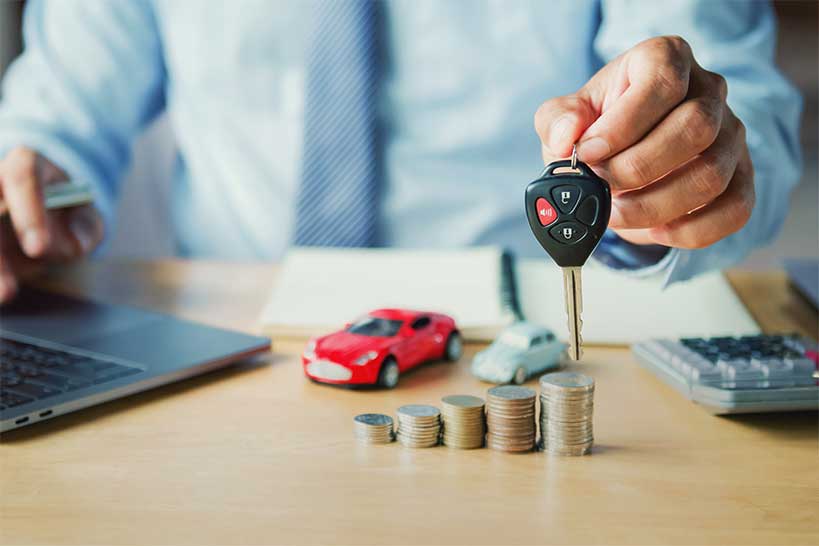 Car keys with a model car and coins for vehicle finance